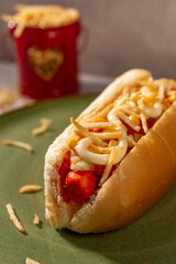 Brazilian Hot dog on green plate with corn and mayonnaise and crispy fries.