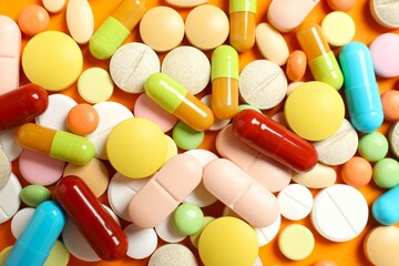 Various medicine pills and capsules on color background 