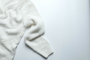 White knitted sweater on paper gray background top view copy space. Texture of woolen cotton winter autumn cozy sweater, clothes. Knitted jumper, pullover, fashion. Sweater close-up