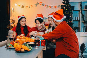 Group of young Asian man and women as friends having fun at a New Year's celebration, holding gift...