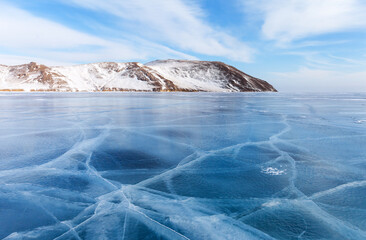 Scenic winter landscape with white cracks on blue ice surface on frozen Baikal Lake on cold sunny...