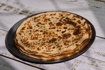 Stack of thin crepes on a wooden board