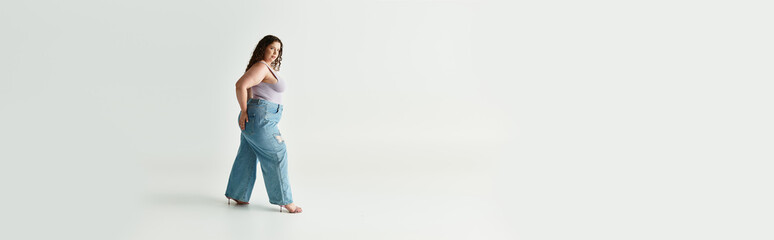 A beautiful young woman strides gracefully in trendy attire within a spacious studio environment.