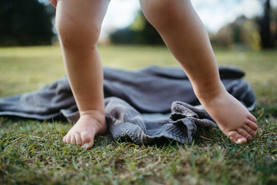 Bare toes of a toddler on the grass with a dropped towel