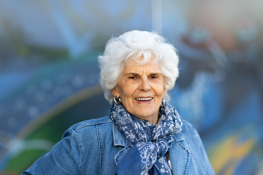 one white-haired lady in her eighties dressed in blue against a blurry blue patterned background