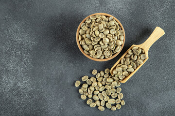 A wooden bowl filled with green coffee beans, top view