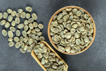 A wooden bowl filled with green coffee beans, top view