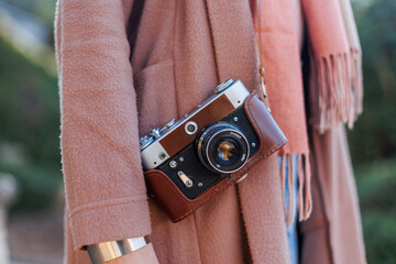 Fashionable look, young woman in a stylish coat with a film camera. Hipster tourist woman with...
