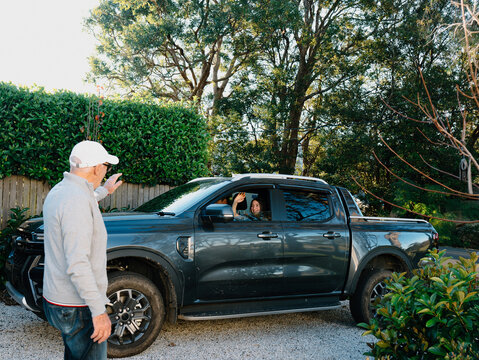 Grandpa waving goodbye to his granddaughter in the car