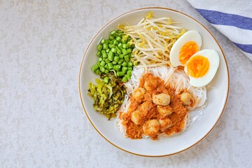 Kanomjeen namya krati ,Rice vermicelli with minced fishes and meatball and coconut milk in red curry on white plate side dish with boiled egg and vegetables