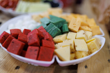 Cheese platter, a variety of cheese cut into cubes. Cheese cubes. White, yellow, green and red cheeses on a plate.