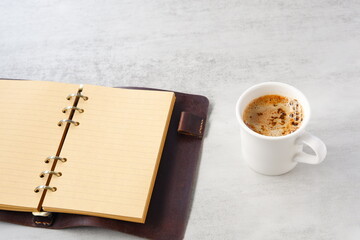 ミルクをたっぷり入れたコーヒー、カフェ・ラッテを飲みながら、システム手帳でデスクワーク中のイメージ
