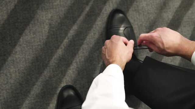 Close-up, successful businessman man tying shoe laces for a social event or banquet. Man's hands tying shoe laces, image of successful wealthy man in elegant black shoes. Concept of celebrating 