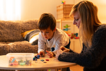 Child and educator playing with modeling clay in kindergarten