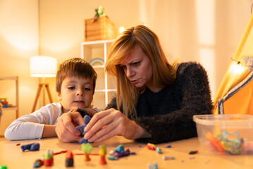 Fototapeta premium Childminder and boy playing with modeling clay at home