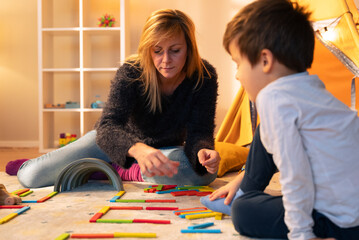 Child psychologist playing with colorful wooden blocks with a child in the playroom