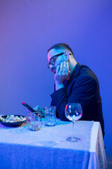 Lonely businessman using smartphone at dinner table in blue light