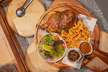 Top view, Half chicken baked in oven with mixed garden salad and french fries