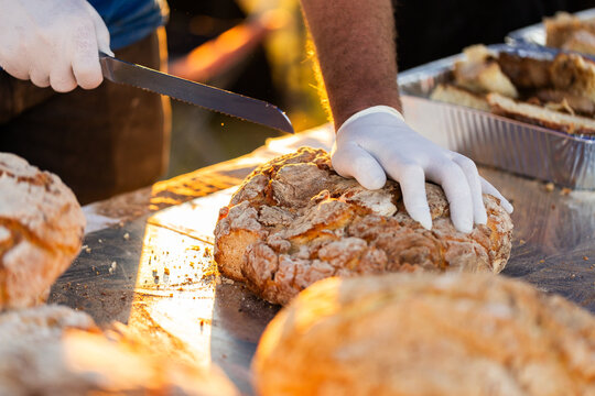 Mans hands cutting camp oven damper bread with knife