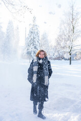 Portrait of a red-haired teenage girl walking in the snow on a winter morning. A walk on a winter day.