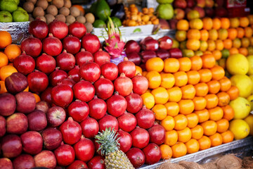 A colorful assortment of fruits, including apples, oranges, and pineapples, at a local Indian market, offering a vibrant scene of health and abundance.