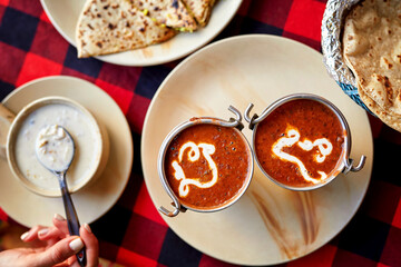Indian dining setup with Dal Makhani served in copper bowls, accompanied by naan, papad, and yogurt dip, showcasing a blend of traditional flavors.