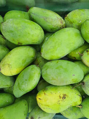 Several green mangoes for sale at a market in Bangkok, Thailand.