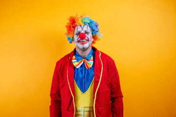 Fototapeta premium Happy clown in colorful costume against vibrant yellow background.