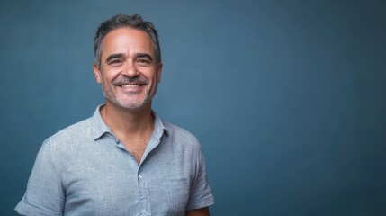 Obraz premium Happy mature man in his forties wearing casual shirt standing isolated on blue background. Smiling middle aged professional businessman looking at camera. Headshot vertical portrait.