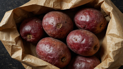 Obraz premium Several dark reddish-purple potatoes are nestled in a brown paper bag.