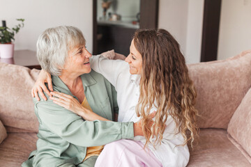 Older mature mother and grown millennial daughter laughing embracing, caring smiling young woman embracing happy senior middle aged mom