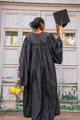 A you black woman wearing a graduation gown looking excited to be a graduand
