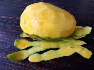 A ripe mango with its skin peeled, the flesh looks yellow, looks attractive with a dark brown background. Mango is one of the favorite fruits in Indonesia