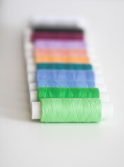 Many colorful sewing threads on light background.