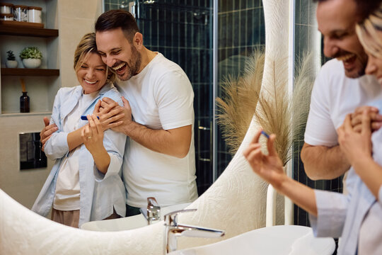 Reflection in  mirror of cheerful couple in bathroom.
