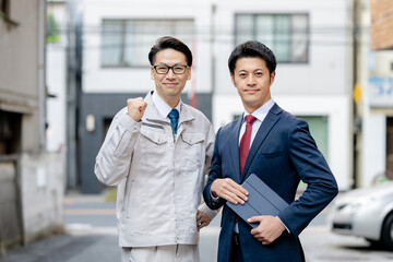 作業着姿とスーツ姿の男性2人