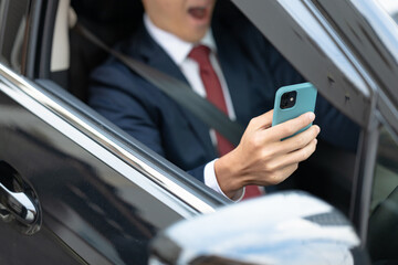 車内でスマホを操作するビジネスマン手元