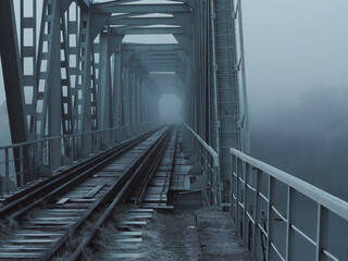 a frozen Old railway bridge in frost . Thick fog in winter landscape