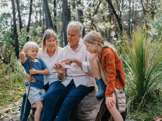 Grandparents enjoying Australian Bushland with their Grandchildren pointing at cicada bug