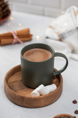 Hot chocolate mug and small marshmallows on wooden saucer