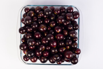 transparent Bowl full of Brazilian fruit jabuticabas on a white background