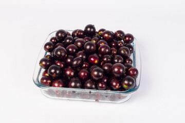 transparent Bowl full of Brazilian fruit jabuticabas on a white background
