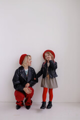 The girl looks at the girl and smiles. They are dressed in family style. They're wearing red berets and they're very stylish.