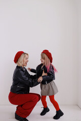 Mom and daughter in red berets are having fun, freaking out, smiling. A woman in red trousers, a girl in tights