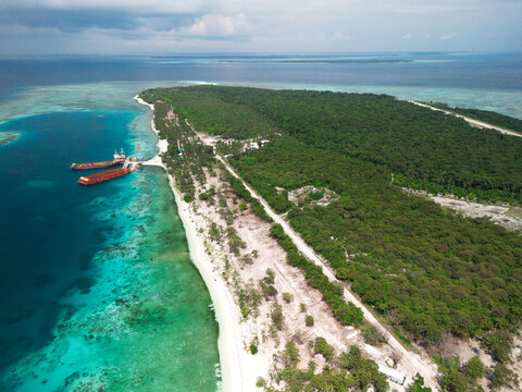 An aerial view of Starfish Island in Balabac, Philippines, showcasing lush greenery, a sandy coastline, turquoise waters, and docked barges