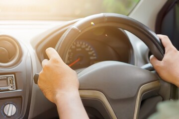 close up A person gripping the steering wheel of a car, focused on driving.