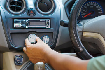 A driver adjusts the air conditioning control while seated in the driver's seat.