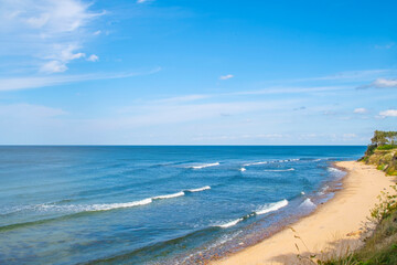 Sandy seashore with green thickets. Trees and bushes on the slopes of the shores near the sea.