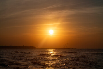 Calm ocean at sunset. Bright orange sun setting in the late evening. Bright path of light on the waves. Romantic seascape.