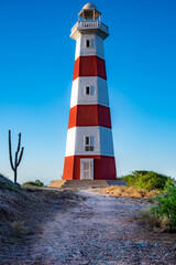 A lighthouse is on a hill with a clear blue sky